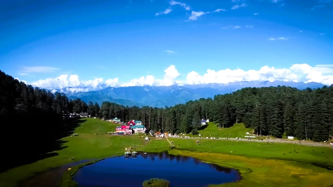 Khajjiar lake and meadow with distant snowy peaks near Dalhousie