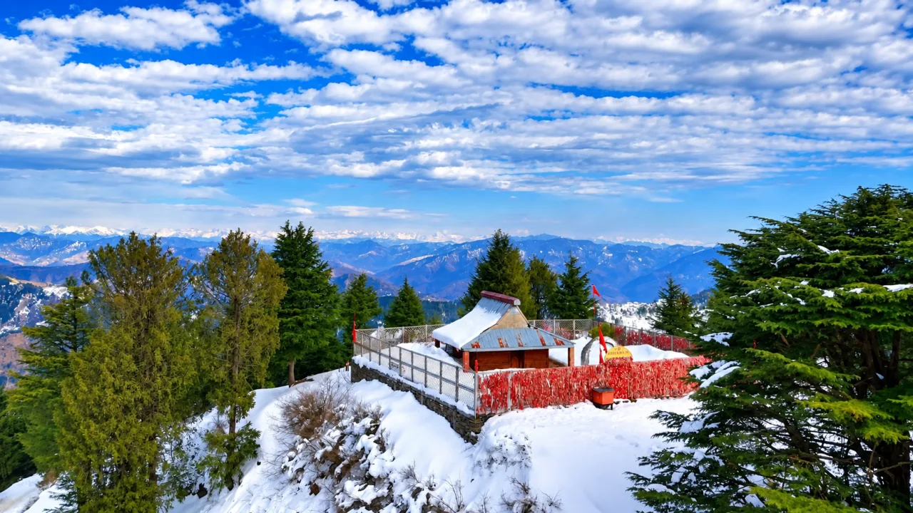 Snow-covered Nag Devta temple at Mahasu Peak in Kufri with Himalayan peaks behind